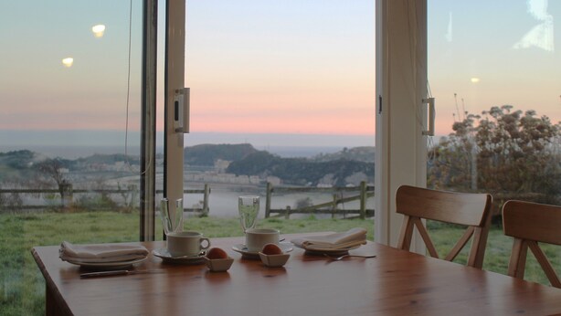 A dining table with a view of a landscape through large windows. - Hotel Mirador del Sella (Ribadesella)