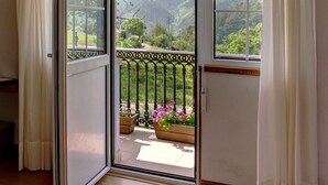 A room with a sliding glass door leading to a balcony with a metal railing and potted plants. - Hotel Mirador del Sella (Ribadesella)