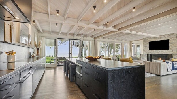 A spacious kitchen with a large island, wooden ceiling beams, and a stone fireplace. - Clay Banks Lakehouse · Door County Lake House 50 min from Lambeau Field (Algoma)