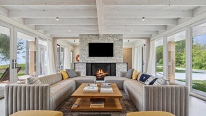 A modern living room with a stone fireplace, large windows, and a comfortable seating area. - Clay Banks Lakehouse · Door County Lake House 50 min from Lambeau Field (Algoma)