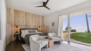 A modern bedroom with a large bed, two armchairs, a small table, and a view of the beach. - Clay Banks Lakehouse · Door County Lake House 50 min from Lambeau Field (Algoma)