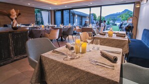Restaurante com mesas preparadas para refeições, com vista para montanhas e uma grande janela.