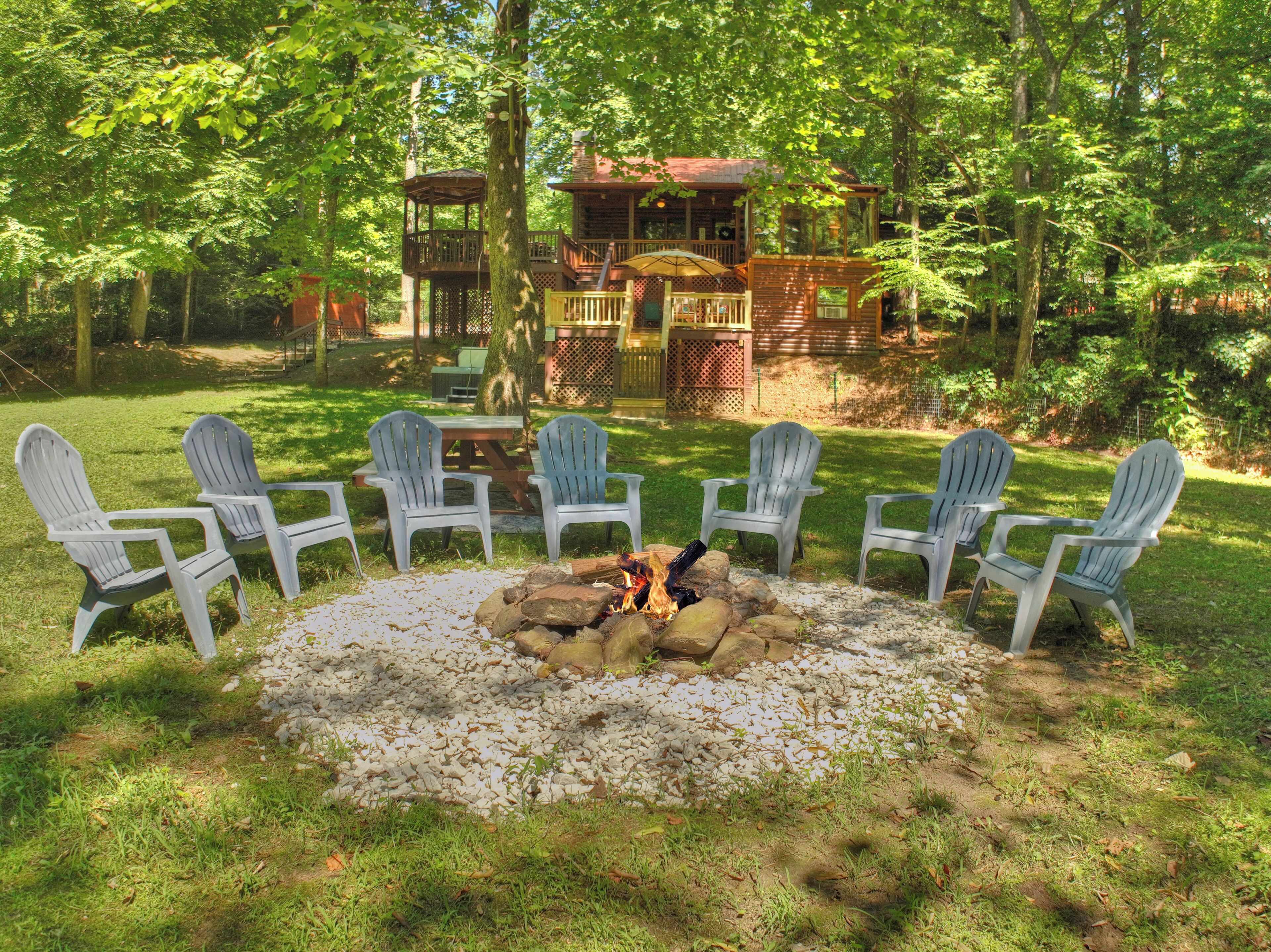 Une terrasse en bois avec des fauteuils Adirondack disposés autour d’un foyer en pierre.