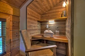 Een houten interieur met een stoel, een tafel en een plank vol boeken.