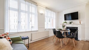 A modern living room with a fireplace, a dining area, and large windows. - Charming Flat in Covent Garden (Greater London)