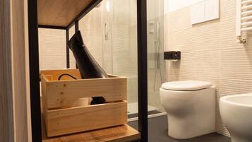 A modern bathroom with a glass shower enclosure, a white toilet, and a wooden storage unit with a black object inside.
