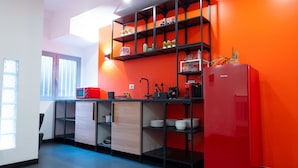 Een moderne keuken met een rode koelkast, zwarte planken en een raam met zonwering.