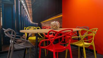 Un coin repas avec une table en bois et des chaises colorées, un bol de collations et un panneau indiquant « MILANO Centrale ».