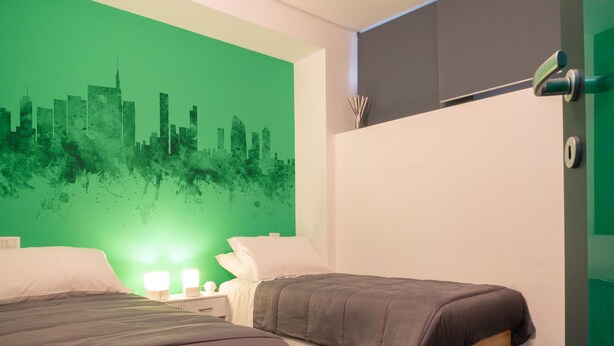 Een moderne slaapkamer met twee bedden, een groene stadsgezicht muur en een minimalistisch design.