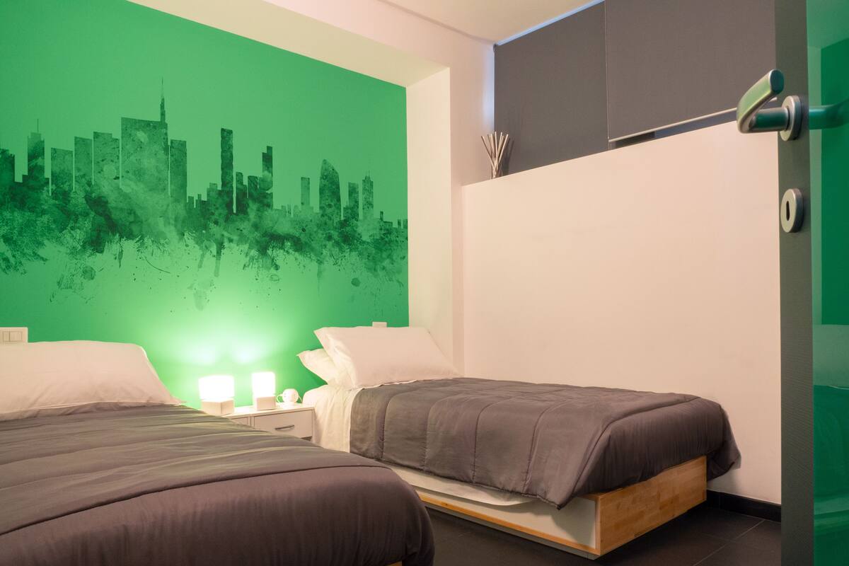 Un dormitorio moderno con dos camas, un mural de paisaje urbano verde y un diseño minimalista.