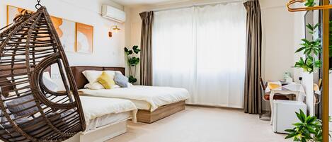 A bedroom with a hanging chair, a bed, a desk, and a window with curtains.