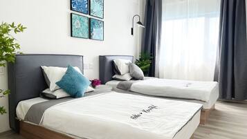 A modern hotel room with two single beds, a large window with curtains, and wall art.
