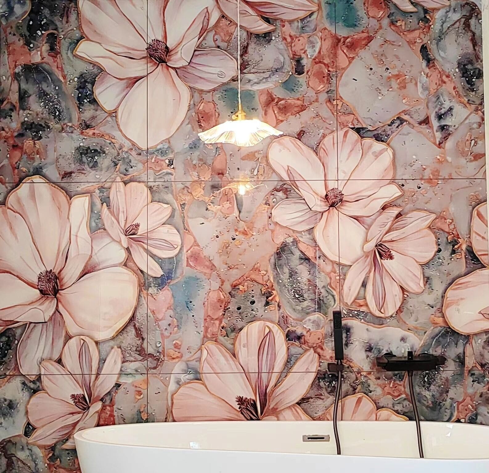 A bathroom with a large floral tile backsplash, a white sink, and a black faucet.