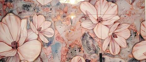 Un baño con un salpicadero de azulejos con motivos florales, un lavamanos blanco y un grifo negro.