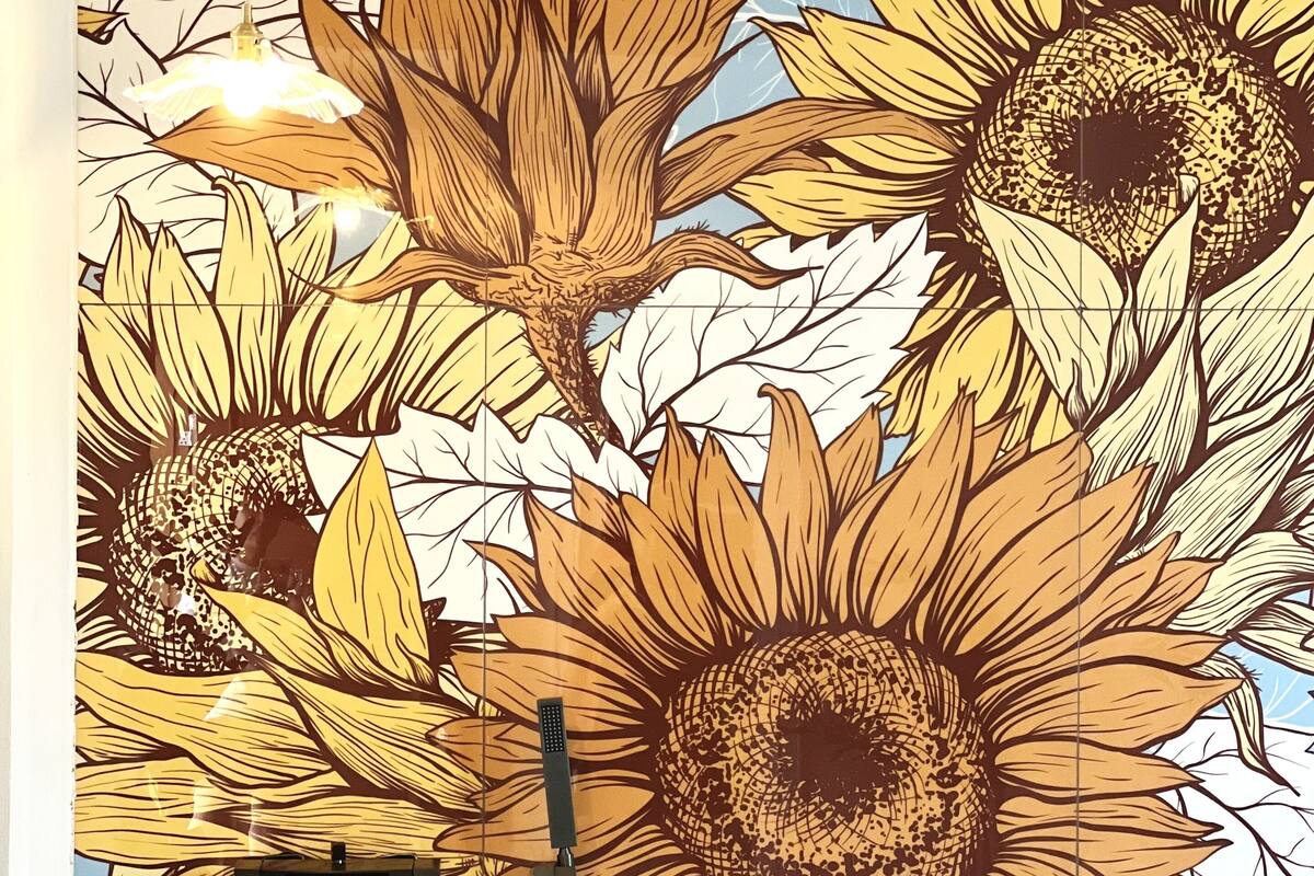 A bathroom with a large white sink and a wall mural of sunflowers.