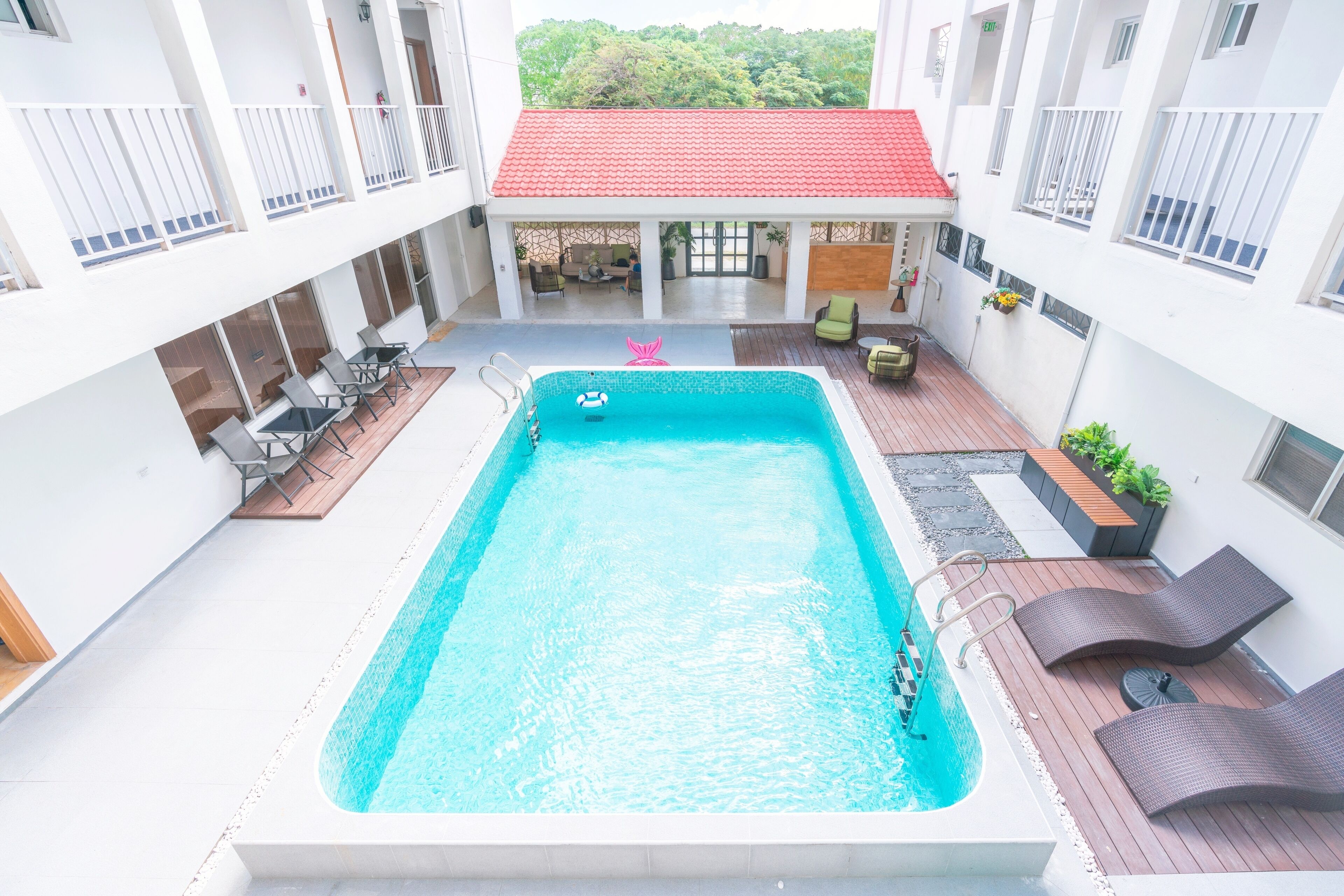 Piscina en la azotea con sillones de descanso y una zona de estar cubierta.