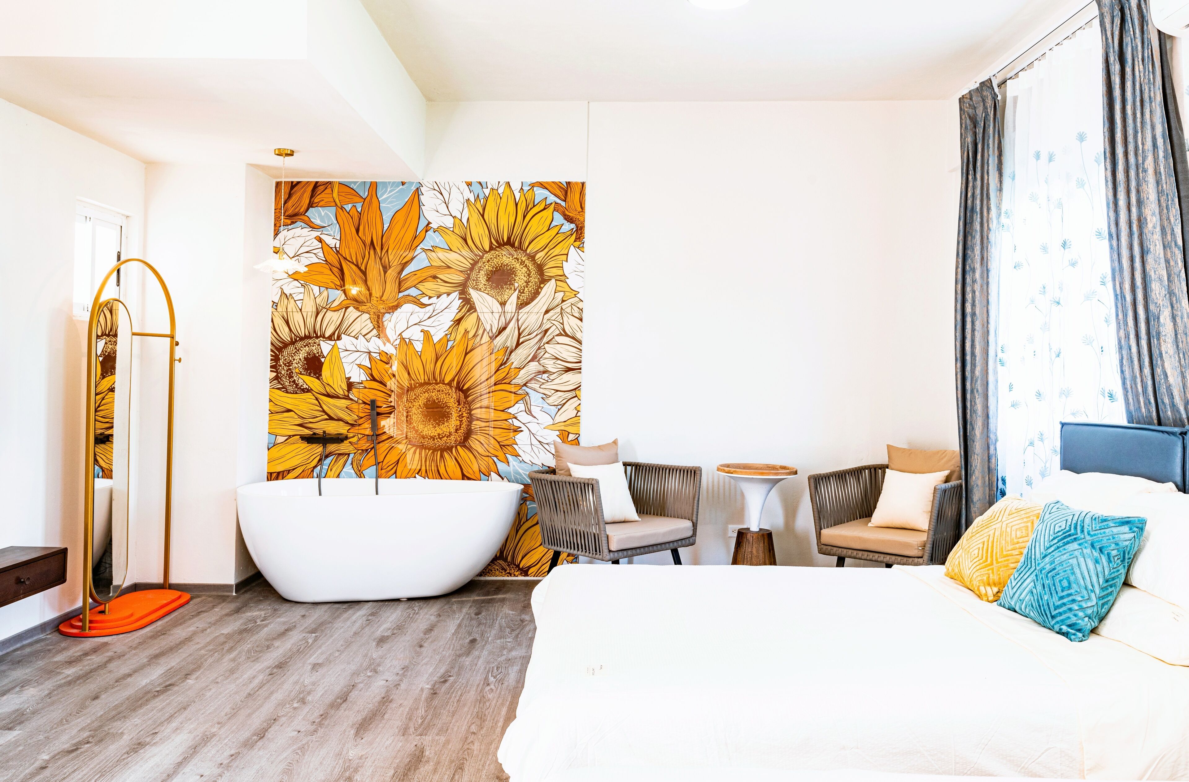 A modern hotel room with a large bed, a bathtub, a chair, and a small table.