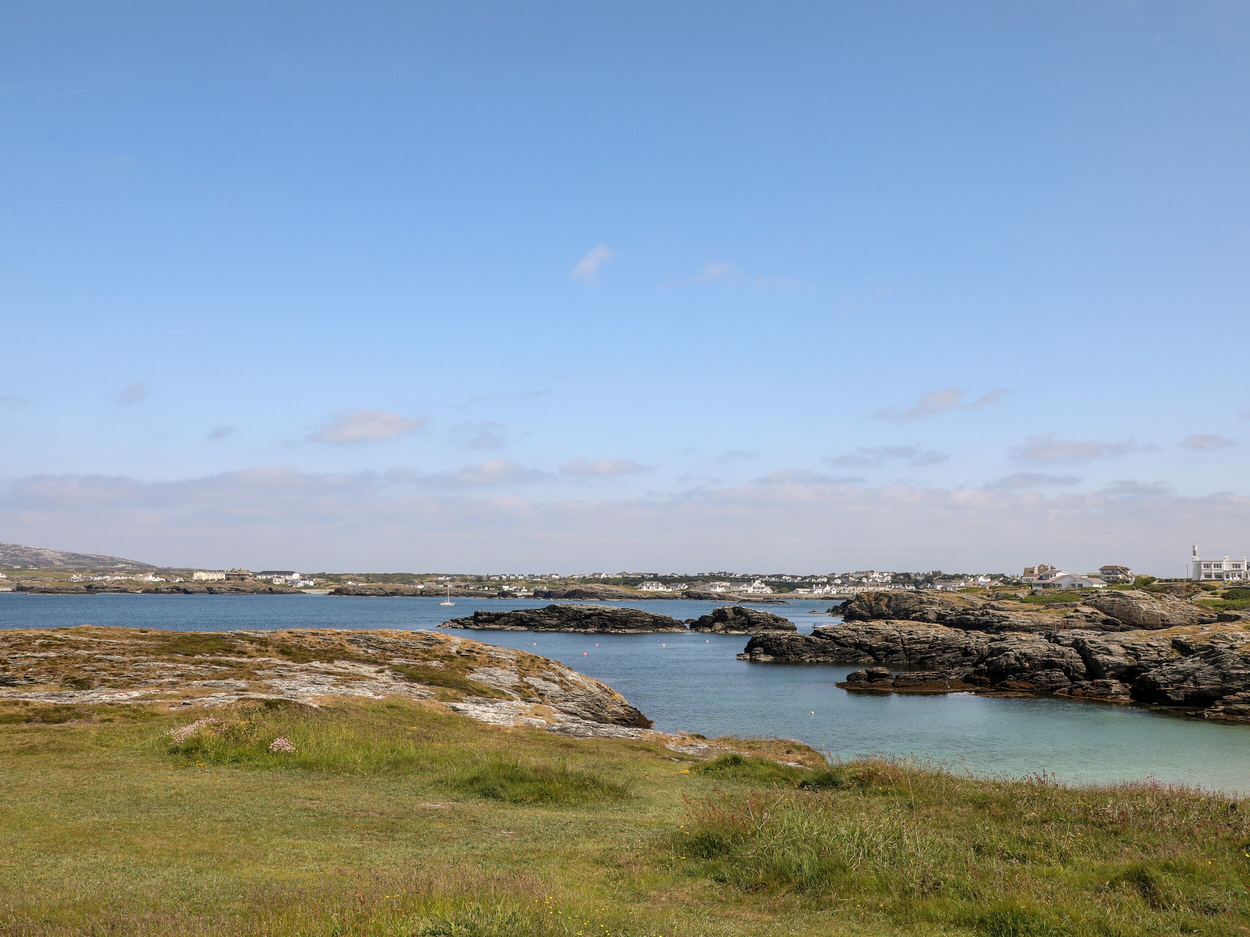 Paesaggio costiero con terreno roccioso, cielo sereno e specchio d'acqua.