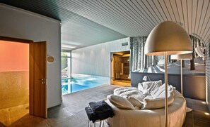 Relax in a spacious room with a large round bed, floor lamp, and stunning pool views.