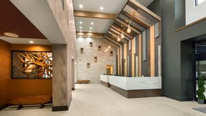 A modern lobby with a reception desk, a large abstract sculpture, and a brick wall. - Beach Getaway Resort View Deluxe King Room 2nd Flr (Myrtle Beach)