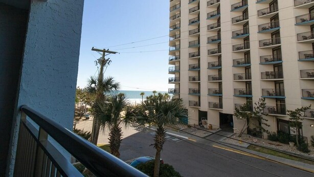 Un hôtel de grande hauteur doté de nombreux balcons, offrant une vue sur la plage et un ciel dégagé.