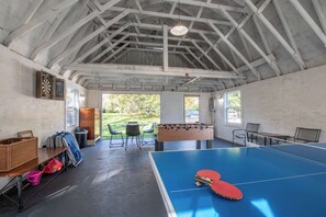 A room with a ping pong table, a foosball table, and a dartboard. - Heated Plunge Pool, Game Barn, AC, 5 Min to Beach! (Chatham)