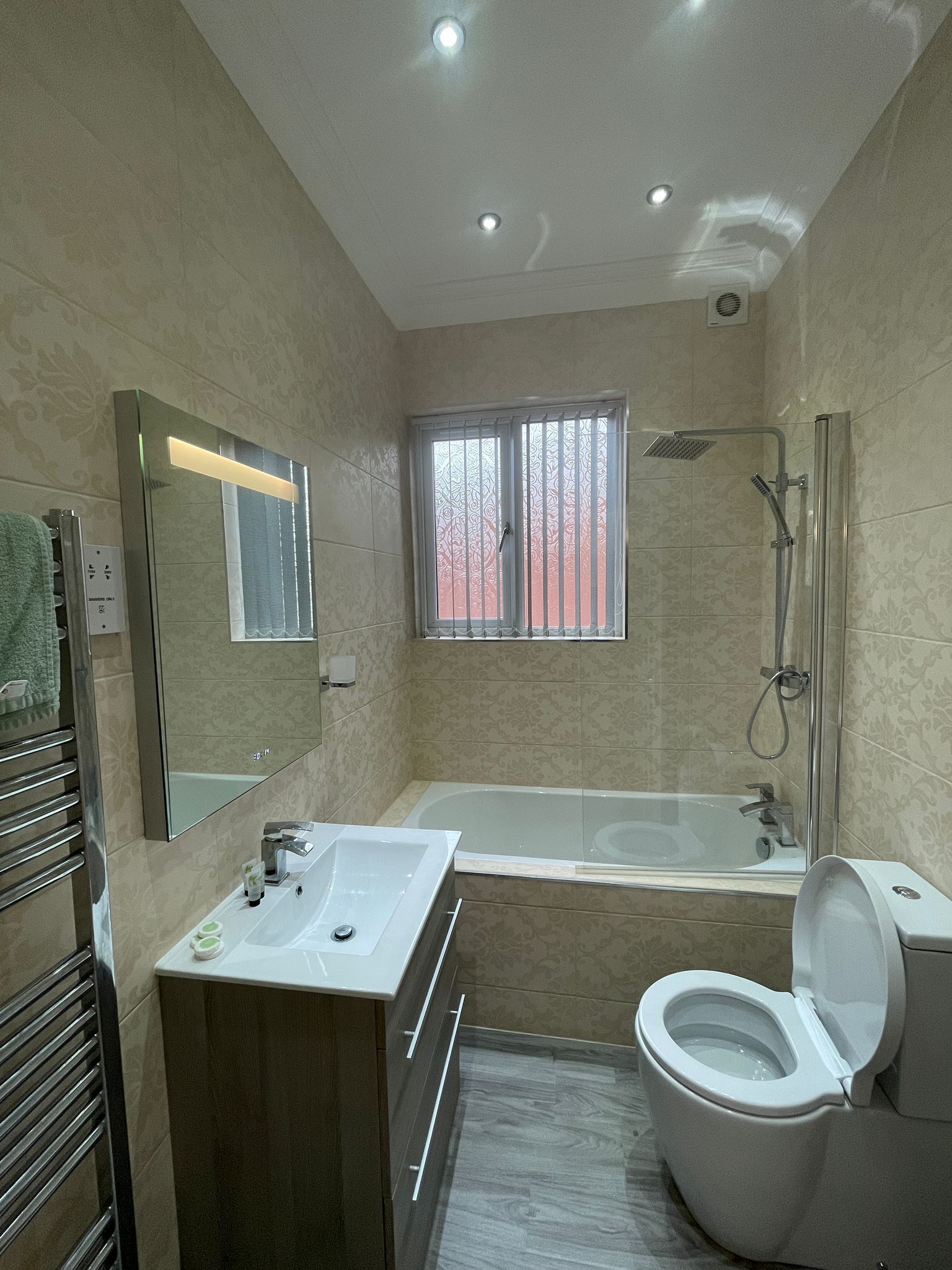 A modern bathroom with a bathtub, toilet, and shower.