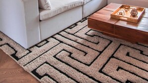 A modern living room with a white sofa, a patterned rug, and a wooden coffee table with decorative items. - Stylish 2 Bedroom, 2 Bathroom Terraced Townhouse & Garden (LONDON)
