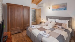 A bedroom with a large bed, wooden wardrobe, and a painting of a sunset over the ocean. - Amazing home in Vrsar (Vrsar)