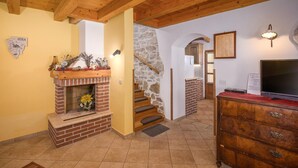 A cozy living room with a brick fireplace, wooden staircase, and a TV on a dresser. - Amazing home in Vrsar (Vrsar)