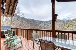 A wooden deck with outdoor seating, overlooking a mountainous landscape. - Abundant Views- Ultra-private and spacious cabin with abundant mountain views! (Sevierville)