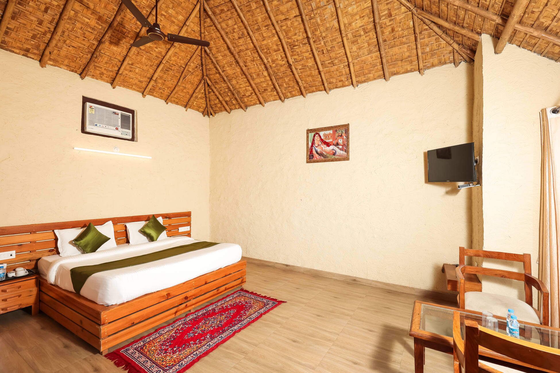 Una habitación con una cama, una mesita de noche de madera, un televisor montado en la pared y una silla.