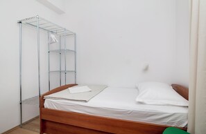 A single bed with a metal shelving unit beside it. - Kate`s place with balcony and amazing sea view for 3 persons (Dubrovnik)