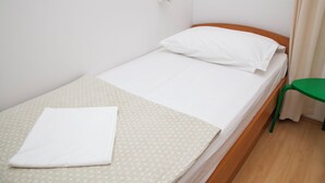 A single bed with a white mattress and pillow, a green chair, and a patterned bedspread. - Kate`s place with balcony and amazing sea view for 3 persons (Dubrovnik)