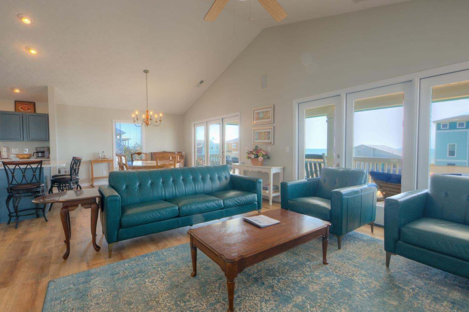 A spacious living room with a large blue sofa, a wooden coffee table, and a dining area with a wooden table and chairs.