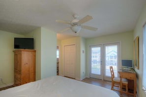 Une chambre à coucher comprenant un lit, une armoire en bois, un ventilateur de plafond et un bureau avec une chaise.