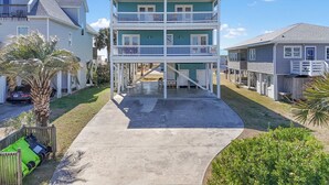 Une maison à deux étages située en bord de mer, dotée d’un balcon, d’une allée et d’un palmier.