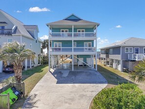 Une maison à deux étages située en bord de mer, dotée d’un balcon, d’une allée et d’un palmier.