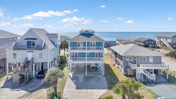 Une propriété située en bord de mer, comprenant plusieurs maisons, dont un bâtiment à deux étages doté d’un balcon et d’un porche avant couvert.