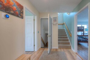 A hallway with a wooden floor, a door leading to a staircase, and a painting on the wall.