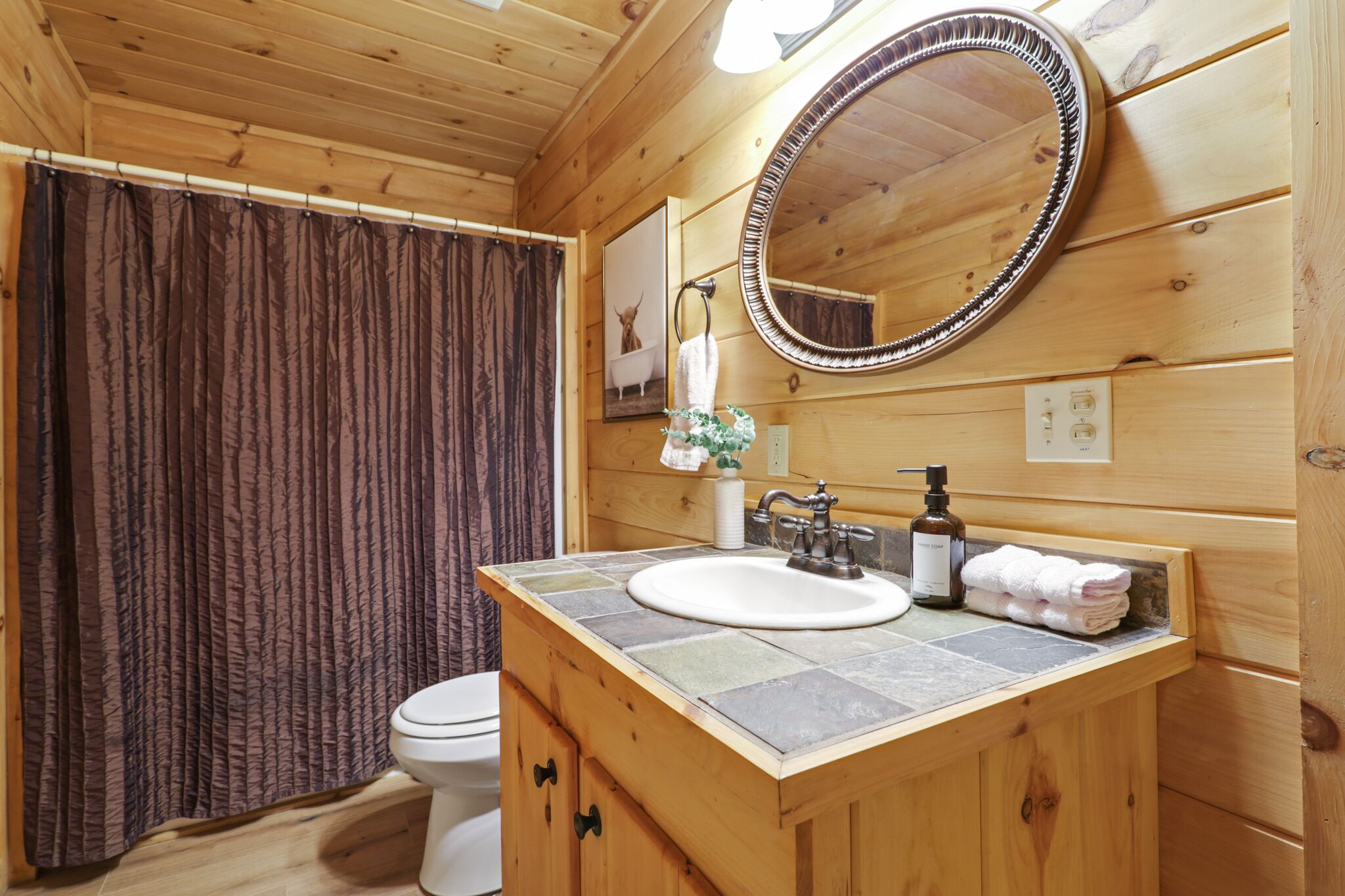 Een houten badkamer met een toilet, wastafel en spiegel.