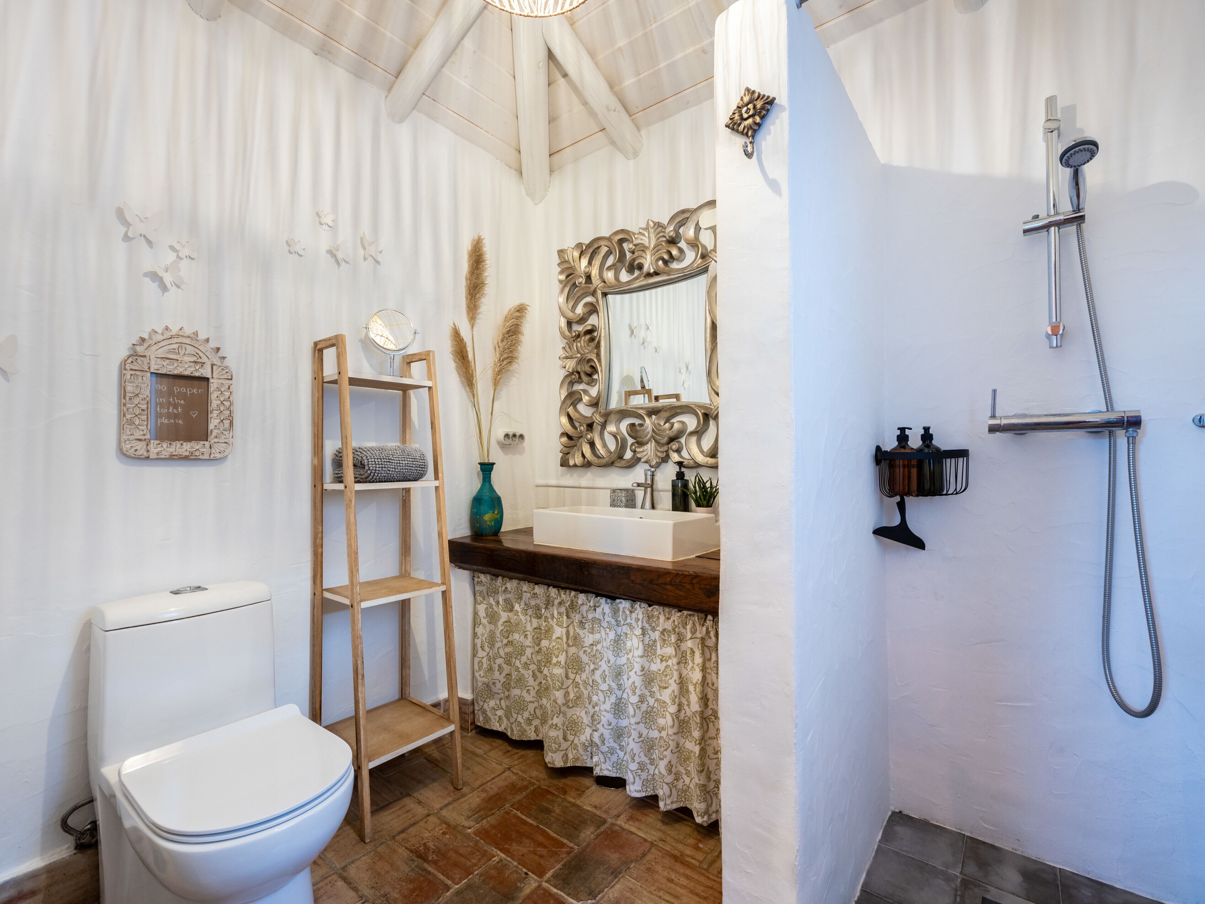 Une salle de bain comprenant des toilettes, une étagère en bois, un miroir, un lavabo et une douche.
