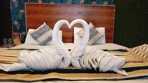 A bed with a heart-shaped towel arrangement and decorative pillows. - Hotel Nirbana Heights (Dharamshala)