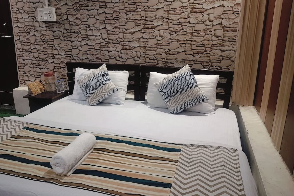 Una cama con ropa de cama a rayas, dos almohadas con estampado de rombos y una toalla enrollada.