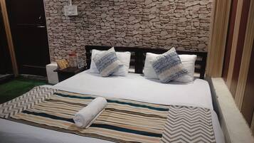 A bed with striped bedding, two pillows with a chevron pattern, and a rolled towel.