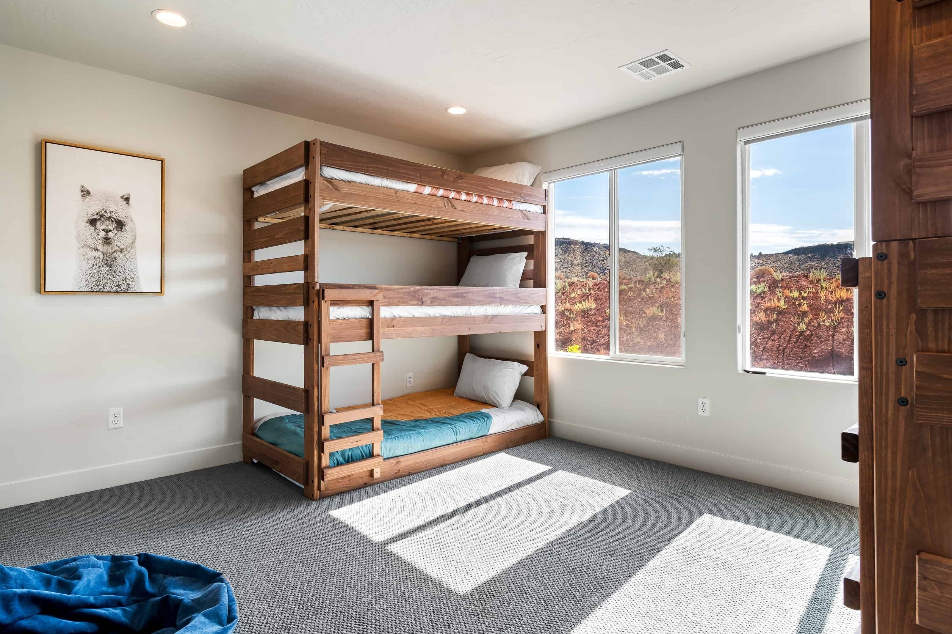 A room with a bunk bed, large windows, and a framed picture on the wall.