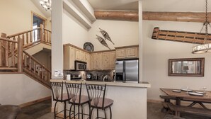 A kitchen with wooden cabinets, a stainless steel refrigerator, and a wooden island with bar stools. - Antler Way At Lakota.... 3 Bedroom Townhouse by RedAwning (Winter Park)