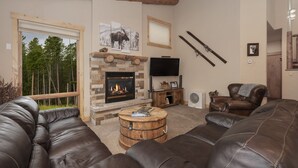 A cozy living room with a stone fireplace, leather sofas, and a television. - Antler Way At Lakota.... 3 Bedroom Townhouse by RedAwning (Winter Park)