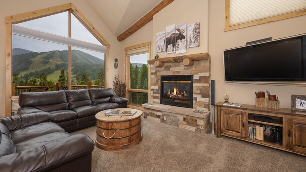 A cozy living room with a fireplace, leather sofa, and a large TV. - Antler Way At Lakota.... 3 Bedroom Townhouse by RedAwning (Winter Park)