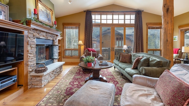 A cozy living room with a stone fireplace, a large window, and a green sofa. - 45 Thackwell Lane 4 Bedroom Townhouse by RedAwning (Keystone)